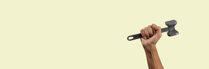 Black male hand holding a kitchen hammer isolated on green background banner