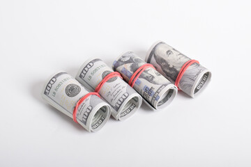 Dollar roll wrapped with red rubber. 100 dollar bills on a roll isolated on white background. Rolled American dollars banknotes