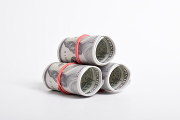 Dollar roll wrapped with red rubber. 100 dollar bills on a roll isolated on white background. Rolled American dollars banknotes