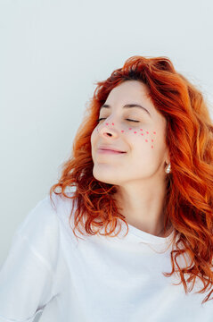 Smiling woman with heart stickers on face against white background