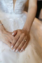 Close-up of a Bride's Hands, Fingernails Manicured, Resting Delicately on White Wedding Dress