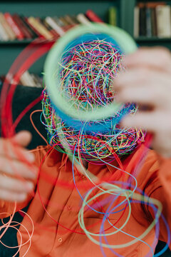 Man with mask of chaotic thoughts holding tangled strings