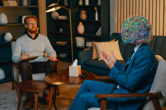 Man wearing mask of chaos discussing problems with psychotherapist in doctor's office