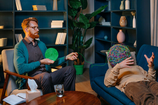 Psychotherapist untangling wire from chaotic mask of patient lying down on sofa
