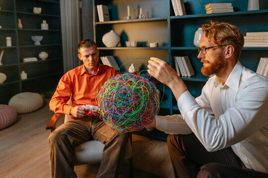 Psychotherapist holding tangling wire from chaotic mask