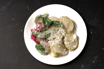A white plate filled with sweet Indonesian treats, Lupis and Cenil, served with grated coconut.