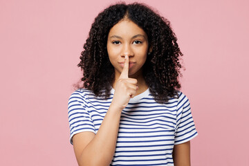 Little kid teen girl wearing blue striped t-shirt casual clothes say hush be quiet with finger on...