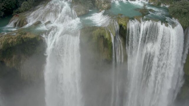 Misty tendrils from waterfall cascading turquoise water in Mexico Jungle