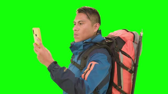 Traveler with yellow smartphone and backpack in green screen studio.