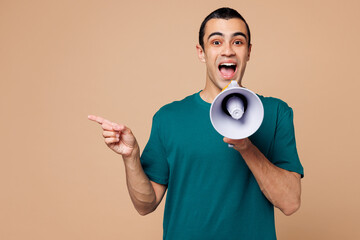 Young surprised middle eastern man wear blue t-shirt casual clothes hold in hand megaphone scream announces discounts sale Hurry up isolated on plain pastel beige background studio. Lifestyle concept.