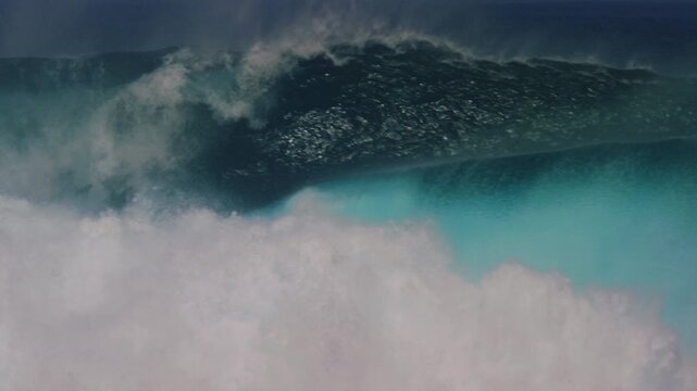 Tracking pan follows crashing dangerous ocean wave erupting with mist and whitewash in slow motion