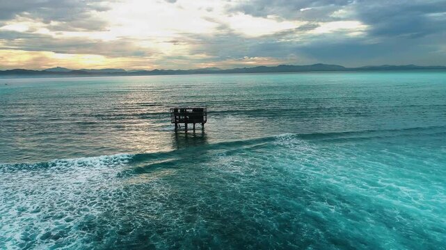 Aerial dolly to judge support tower on stilts at Cloudbreak Fiji at sunset