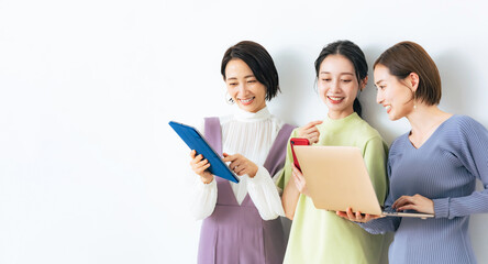 タブレットやスマホを見ながら会話する女性グループ