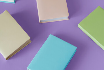 Many colorful books on a pastel purple background with soft shadow, copy space. Book Lovers Day concept