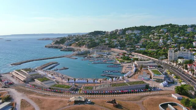 Marseille, France: Aerial view of Marina Olympique, main marina for Olympic Summer Games Paris 2024, flags of participating states flutter in wind - landscape panorama of Europe from above

