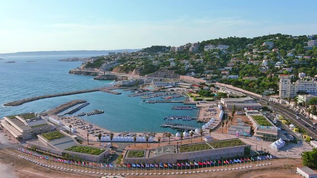 Marseille, France: Aerial view of Marina Olympique, main marina for Olympic Summer Games Paris 2024, flags of participating states flutter in wind - landscape panorama of Europe from above
