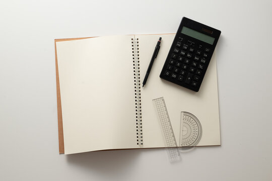 Collective image of stationery.
Notebook, protractor, ruler, calculator and pen.