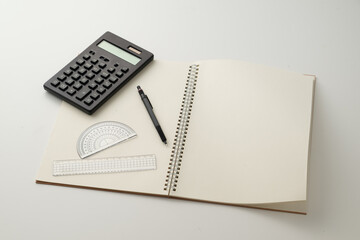 Collective image of stationery.
Notebook, protractor, ruler, calculator and pen.