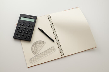 Collective image of stationery.
Notebook, protractor, ruler, calculator and pen.