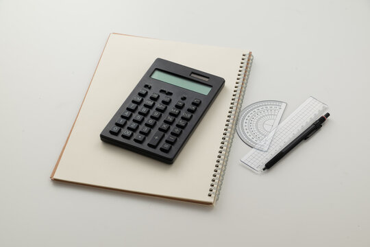 Collective image of stationery.
Notebook, protractor, ruler, calculator and pen.