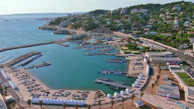 Marseille, France: Aerial view of Marina Olympique, main marina for Olympic Summer Games Paris 2024, flags of participating states flutter in wind - landscape panorama of Europe from above
