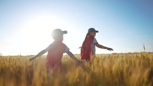 A group of kids playing a video game of superheroe together. Child hero fun concept. Superhero running through the wheat with children. A group of kids sunset playing a game of running together.
