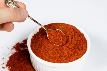 Spice ground smoked paprika on a white background.