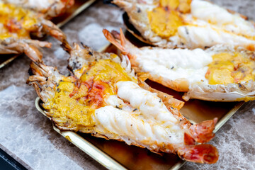 Grilled giant river prawn in a Thai luxury restaurant. Seafood in Thailand. Grilled giant river prawn served on a plate with Thai seafood sauce. Thai cuisine. Grilled giant shrimp on a dinner table.