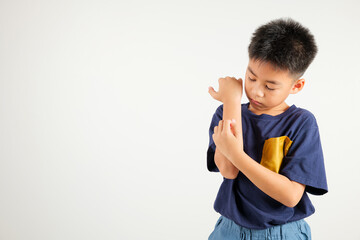 Asian little kid boy scratching itchy arm from a mosquito bite at studio shot isolated on white...