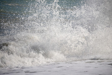 A sea wave breaks against the rocks, water splashes in the sky. Tidal wave.