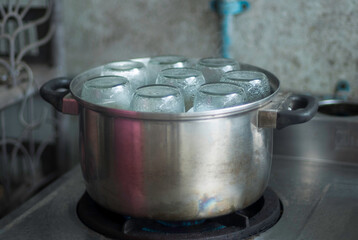 Sterilization bottles by aluminium steamer on the gas stove in kitchen closed up selective focus...