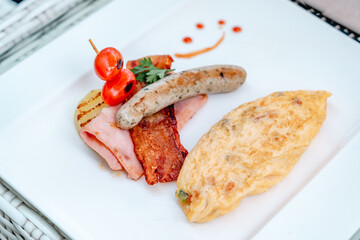 Breakfast in luxury hotel. Table full of various food from buffet in modern resort. Morning food - fresh bakery, glasses of orange juice, eggs, cold cuts and plate with tropical fruits in restaurant
