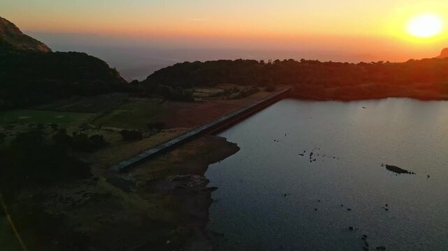 Aerial view golden sunset over Ghatghar Dam and Kokan Kada Bhandardhara surrounded by some very amazing hills Maharashtra India 4K Drone
