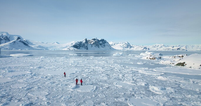 Beautiful winter panorama arctic nature landscape. Aerial fly over frozen polar ocean and snow covered mountains under blue sky. People explore Antarctica discover South Pole beauty. Expedition travel