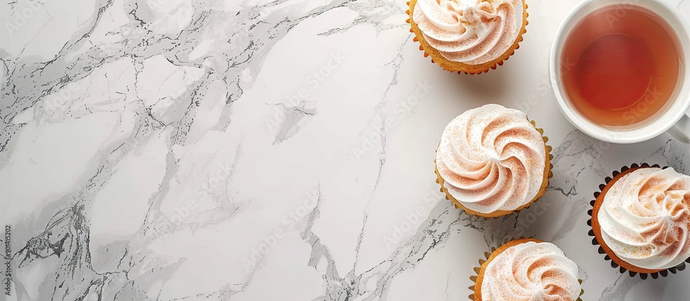 Poster peach cupcakes and a cup of tea on a marble background with copy space image in a top view