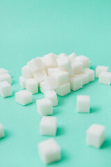White sugar cubes on green background, vertical card of sweet food ingredient