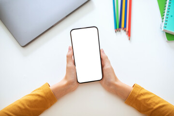 A person is holding a smartphone with a blank screen in their hands. The phone is positioned horizontally, with the screen facing the viewer