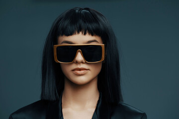 Blackhaired woman in sunglasses and black blazer, dark background