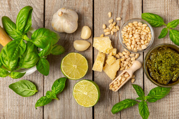 Pesto. Italian basil pesto sauce on a textured wooden background. Ingredient for pesto sauce: fresh basil, pine nuts, Parmesan cheese and olive oil. Space for text.Copy space.