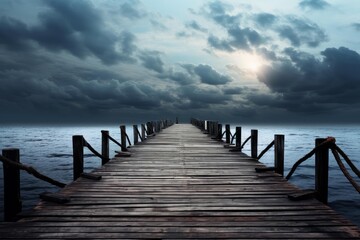 Obraz premium Tranquil scene featuring an old wooden pier stretching into the ocean under a dramatic cloudy sky at dusk