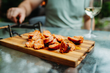 Close up of man hands cutting bbq sausage with knife