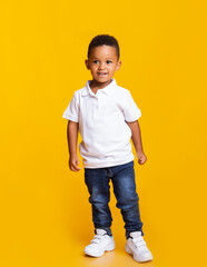 Portrait of cute little black baby boy standing in studio over yellow background, free space
