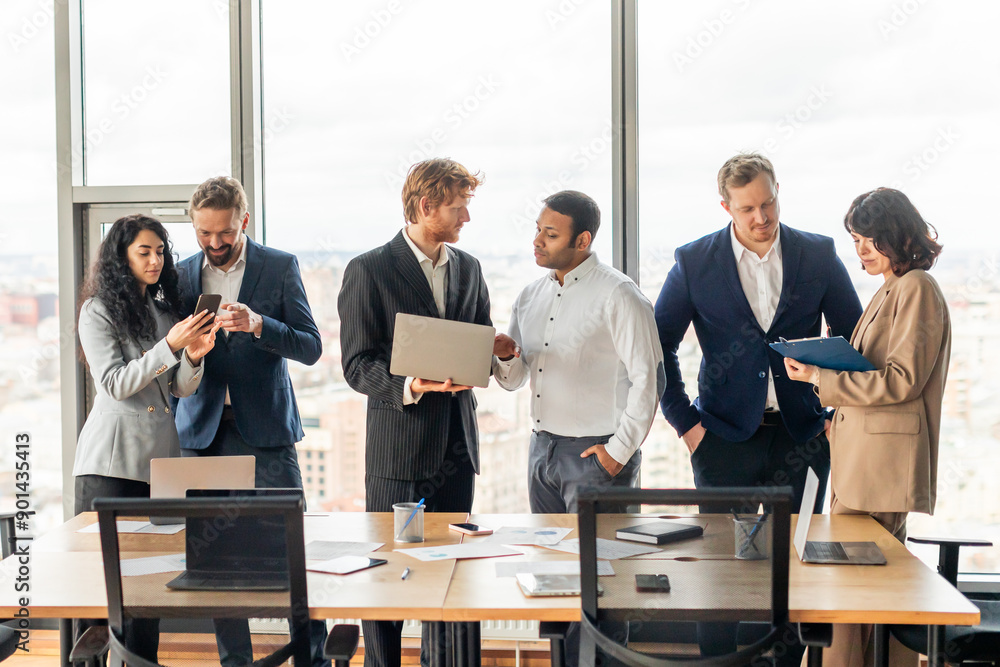 Poster a group of business professionals stand in a modern office space, discussing business while looking 