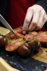 chef cortando tomate con cuchillo en una tabla de cocina