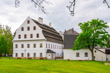 A view of the historic paper mill building in Velke Losiny, Czechia. The building is white with a distinctive roof, showcasing its traditional design.