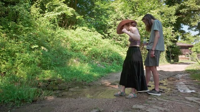 Young teenage playful romantic toe dipping in rural village stream