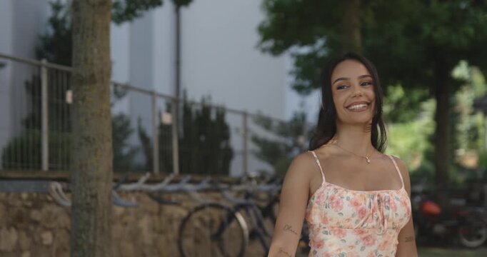 beautiful woman walks and waves to someone and smiles