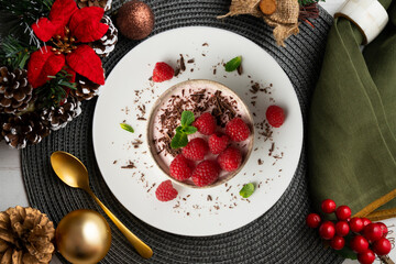 Delicious raspberry mousse with red berries from an overhead perspective. Table with Christmas decoration.