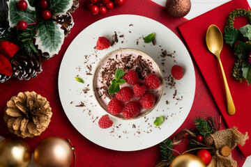 Delicious raspberry mousse with red berries from an overhead perspective. Table with Christmas decoration.