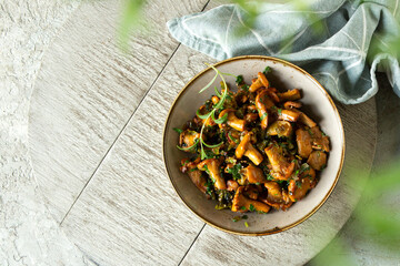 Fototapeta premium bowl with fried chanterelles on a light table, top view